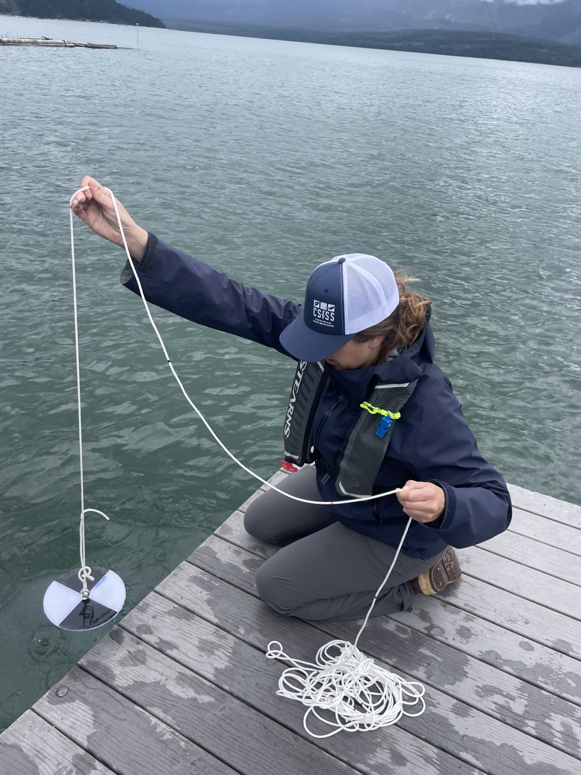 CSISS staff lowering secchi disc into water from a dock.