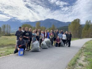 Group of volunteers showing off garbage bags filled with invasive species on the Revelstoke greenbelt trail.